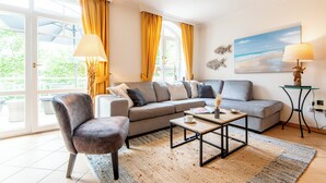 Ein Wohnzimmer mit einer Couch, Sesseln, einem Couchtisch und einem Gemälde an der Wand.