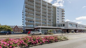 Ein modernes Hotel mit mehrstöckiger Bauweise, überdachter Eingangsparte und Parkplatz mit Autos.