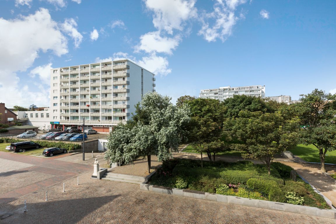 A multi-story residential building with a parking area and landscaped garden.