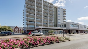 Et moderne hotel med et mereetages byggeri, en overdækket indgang og en parkeringsplads med biler.
