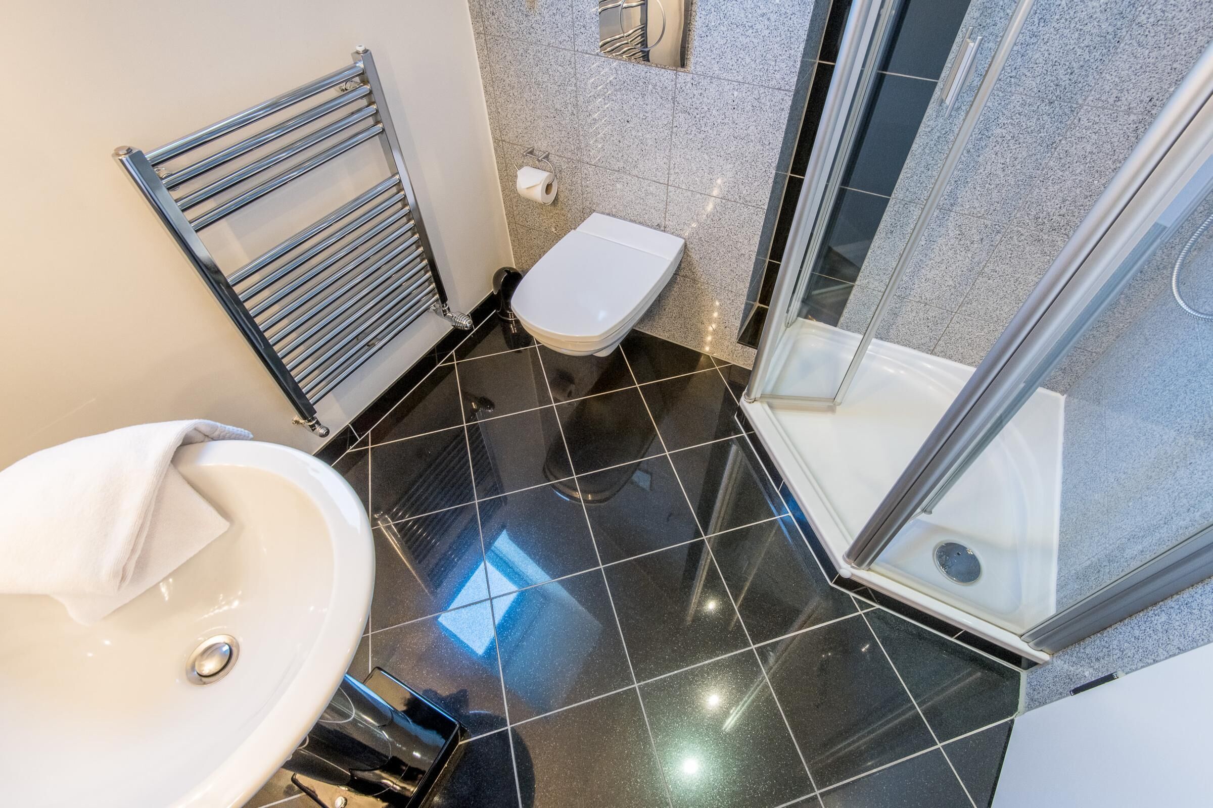 A modern bathroom with a white sink, a glass shower enclosure, and a toilet.