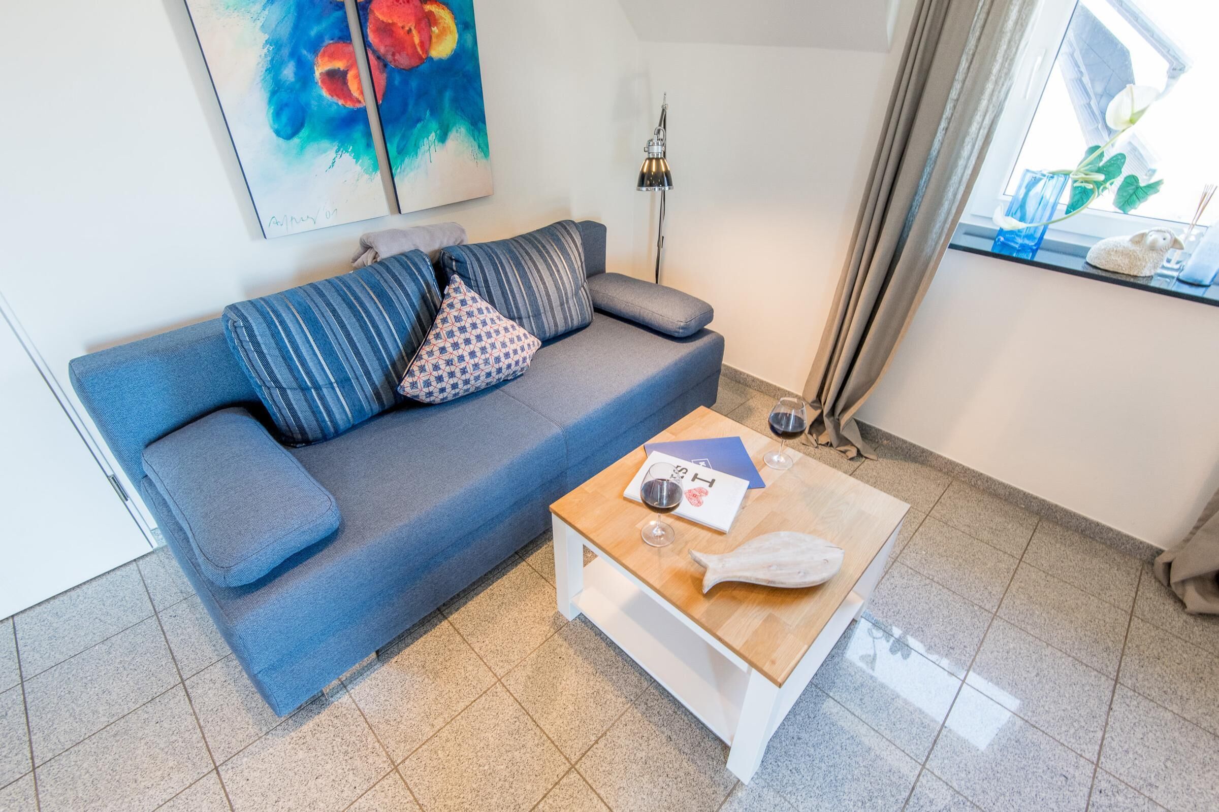 A living room with a blue sofa, a wooden coffee table, and a painting on the wall.