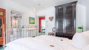 Un dormitorio con una cama grande, un armario de madera, un espejo y una lámpara verde.