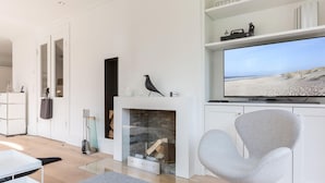 A modern living room with a fireplace, a television, and a comfortable seating area. - Dansk Hus Sylt List (List)