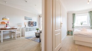 Un dormitorio moderno y bien iluminado con cama, escritorio y televisor.