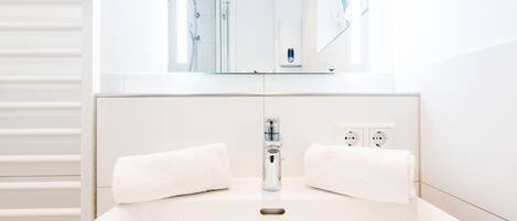 A modern bathroom with a large mirror, a white sink, and two towels.
