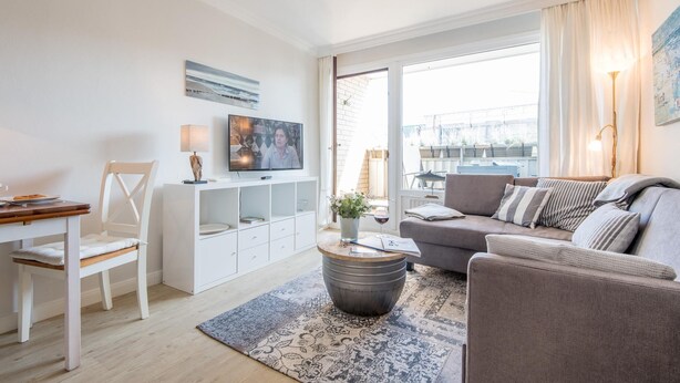 Una sala de estar moderna con un sofá, una mesa de centro, un televisor y un comedor con una silla y una mesa.