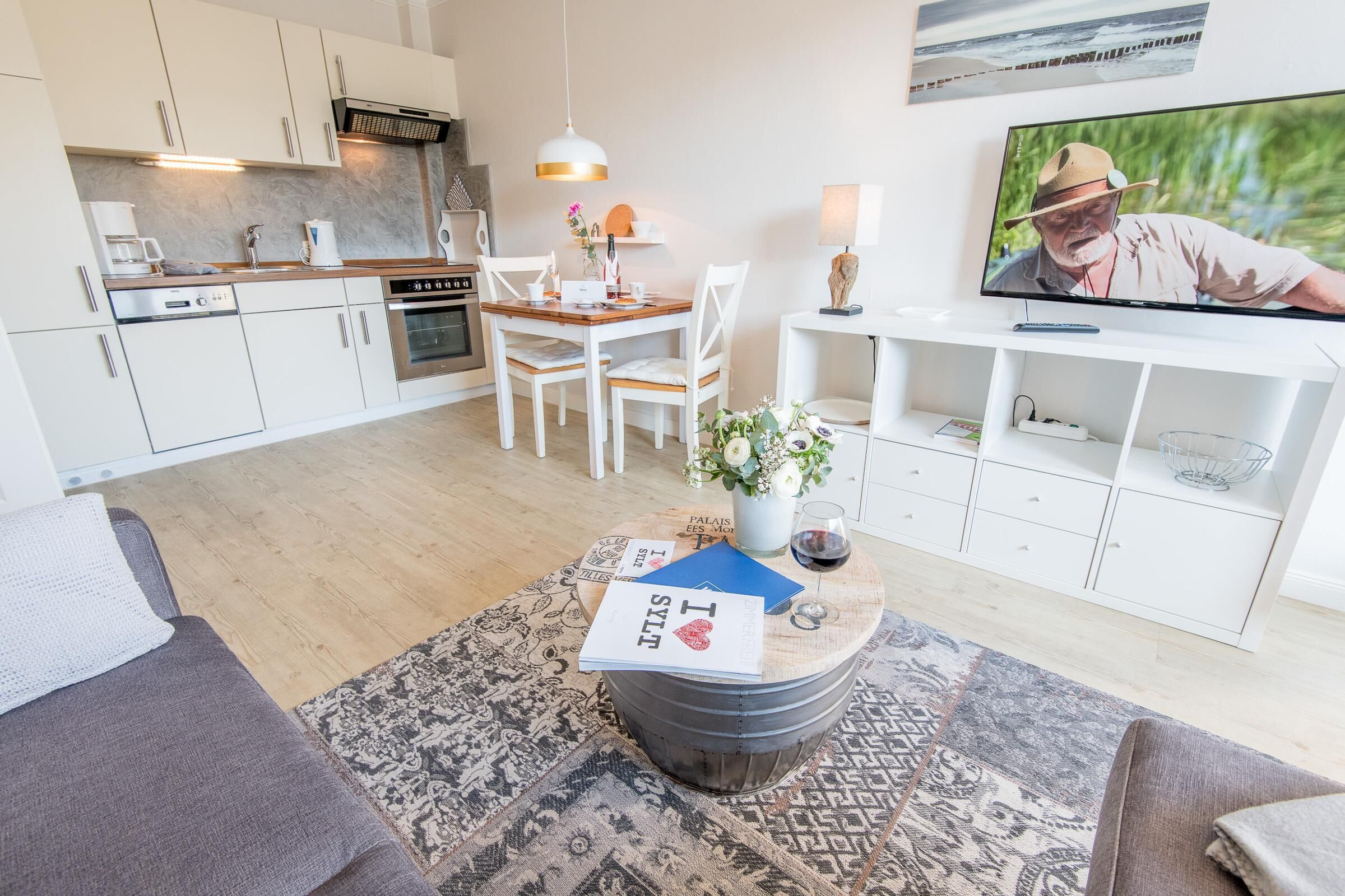En moderne stue med spiseområde, køkken og tv.
