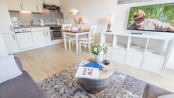 En moderne stue med spiseområde, køkken og tv.