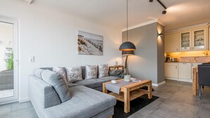 Een moderne woonkamer met een grijze modulaire bank, een houten salontafel en een hanglamp.