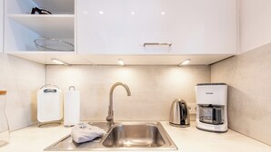 A modern kitchen with a stainless steel sink, a coffee maker, and a kettle. - Gemütlich. Zentral. Strandnah. Objekt-id: Hdb/24 (Westerland)