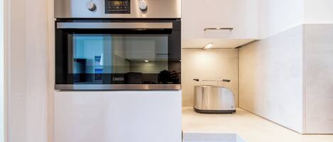 Une cuisine moderne équipée d’un four encastré, d’un grille-pain et d’une hotte en acier inoxydable.