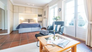 Une chambre à coucher avec un lit, une chaise, une table et une fenêtre.