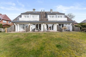 A two-story house with a front porch, a covered patio, and a small backyard.