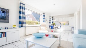 Una cocina moderna con armarios blancos, un tazón azul sobre la mesa y un reloj en la encimera.