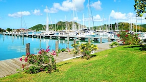 Un puerto deportivo con barcos amarrados, un muelle de madera y una zona verde con flores.