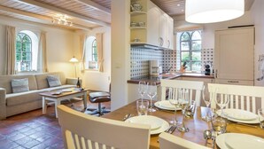 A cozy living room with a dining area set for a meal, featuring a wooden table, chairs, and a sofa. - Ruhig. Edel. Garten. Haus Mühlenhof, Whg. 4 Objekt-id: Mht/04 (Westerland)