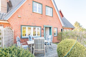 A brick house with a deck, a wooden gate, and a number '24B' on the wall.
