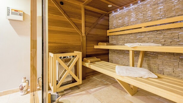 Una sauna de madera con bancos y una pared de piedra.