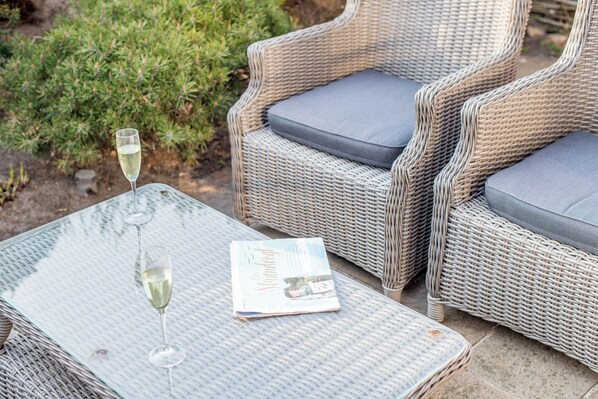 Wicker furniture with cushions, a glass table, and a magazine.