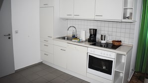 A kitchen with white cabinets, a dishwasher, an oven, and a coffee maker. - Posthus Apartment 303 with balcony, close to the beach and central (Borkum)