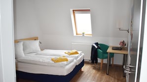 A bedroom with a bed, a desk, a chair, a window, and a radiator. - Posthus Apartment 303 with balcony, close to the beach and central (Borkum)