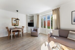 A modern living room with a dining area, a television, and a view of the outside. - Gemütlich. Strandkorb. Ruhig. Senwai-hüs, Whg. 2 "keitum" Objekt-id: Hsw/02 (Westerland)