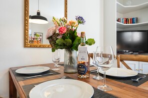 A dining table set with white plates, two wine glasses, a bottle of wine, and a vase with flowers. - Gemütlich. Strandkorb. Ruhig. Senwai-hüs, Whg. 2 "keitum" Objekt-id: Hsw/02 (Westerland)