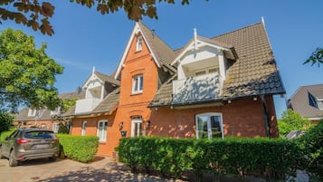 A two-story house with a red brick facade, white trim, and a tiled roof.