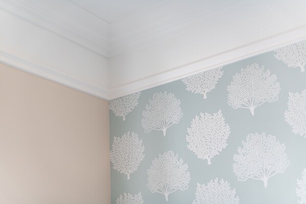 A room with a light blue wall featuring a pattern of white tree silhouettes. - Strandnah. Zentral. Gemütlich. Stadthaus Boysenstraße, Whg. 4 Objekt-id: Shb/04 (Westerland)
