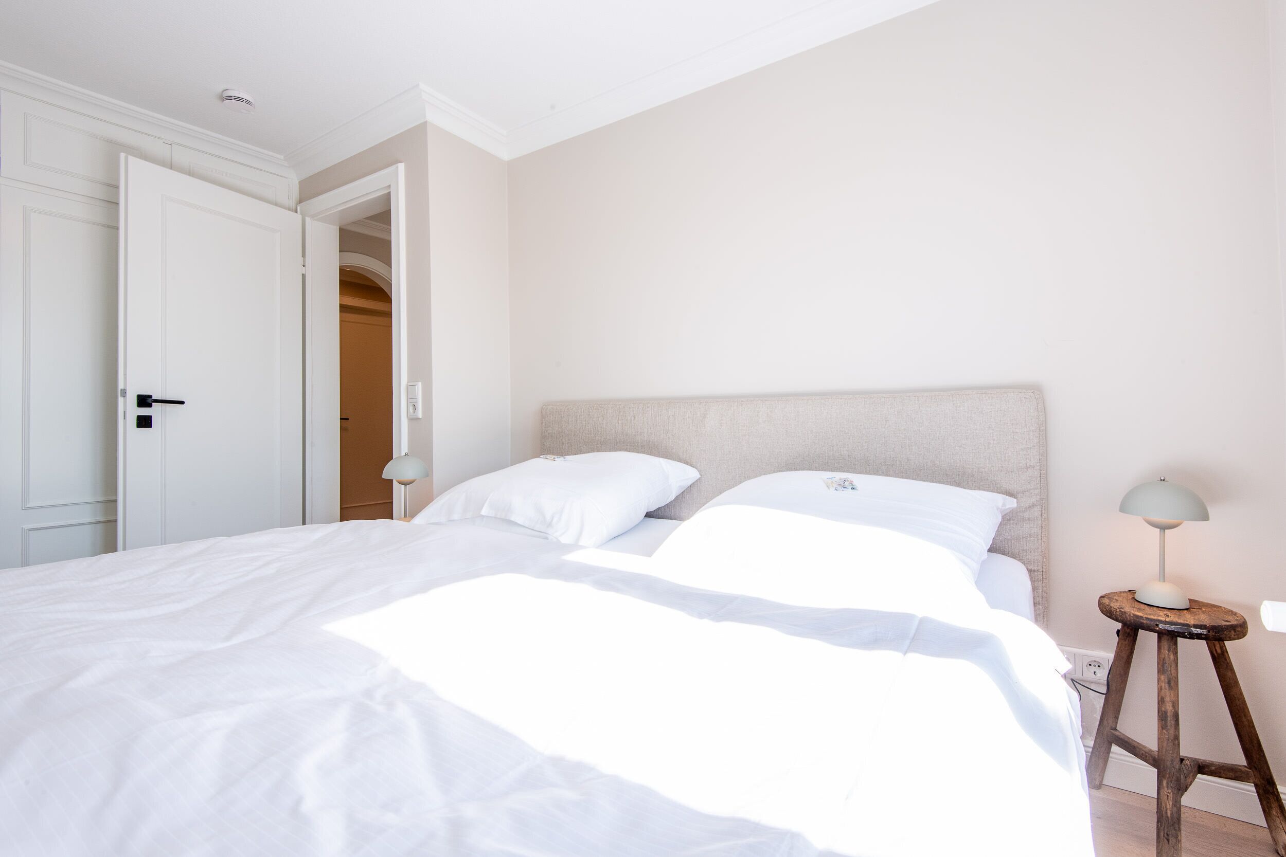 A bedroom with a bed, a nightstand, a lamp, and a door.