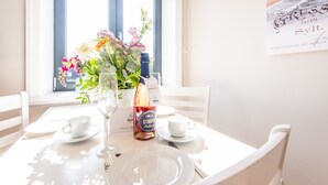 Una mesa de comedor con una botella de vino, dos vasos y un jarrón de flores.