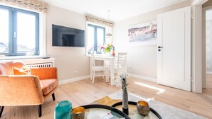 Una sala de estar moderna con sofá, una mesita de centro de vidrio y una zona de comedor con mesa y sillas.