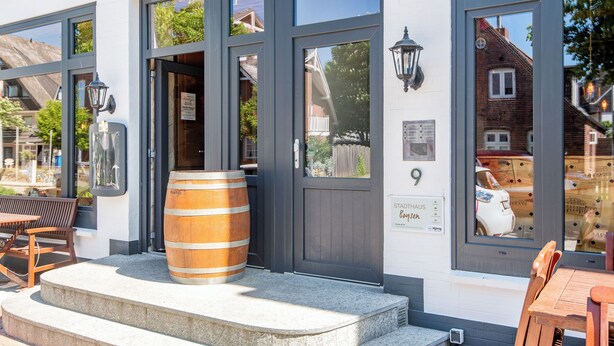 A building with large windows, a wooden barrel, and outdoor seating. - Stadthaus Boysenstraße, Whg. 7 Ruhig. Gemütlich. Strandnah. Objekt-id: Shb/07 (Westerland)