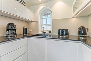 A modern kitchen with a central island, built-in appliances, and a large window providing natural light.