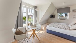 A modern bedroom with a bed, a round table, and a chair. - Stylish. Lichtdurchflutet. Sauna (Westerland)