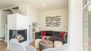 A modern living room with a fireplace, a sofa set, and a decorative wall piece. - Stylish. Lichtdurchflutet. Sauna (Westerland)