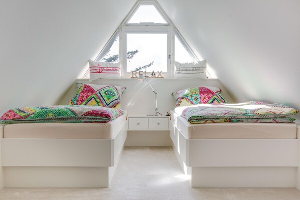 Une chambre avec deux lits, une fenêtre et une table de chevet.