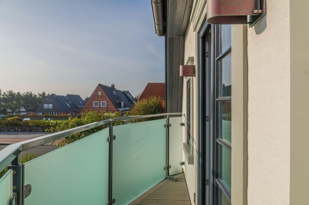 A balcony with a glass railing overlooking a residential area.