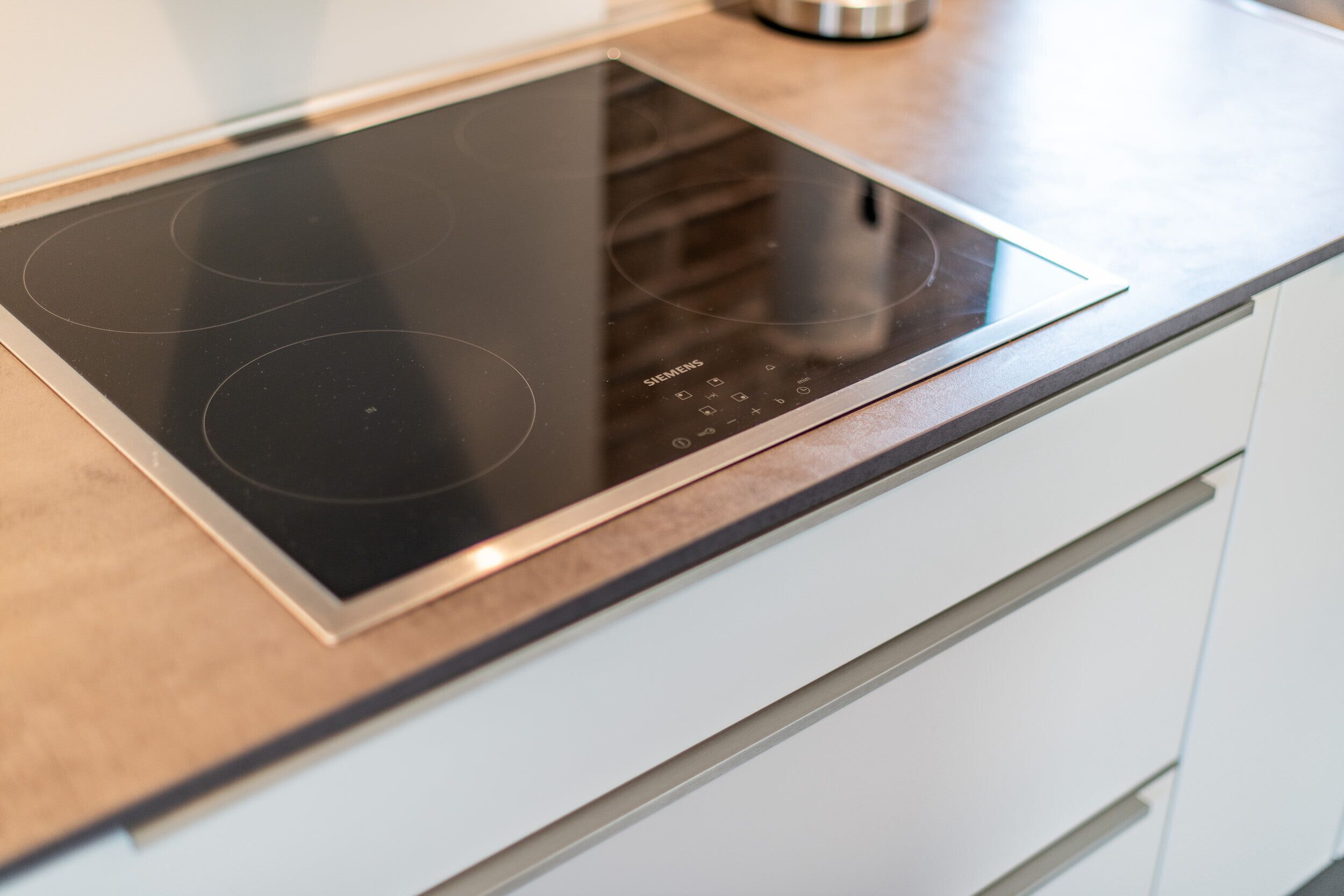 A modern kitchen with a built-in Siemens induction cooktop and a stainless steel kettle.