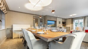 Un comedor moderno con una larga mesa de madera dispuesta para seis personas, rodeada de sillas tapizadas.