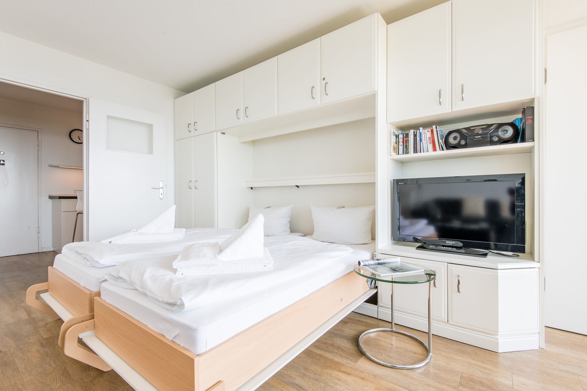 Una habitación de hotel moderna con una cama, un televisor y una estantería.