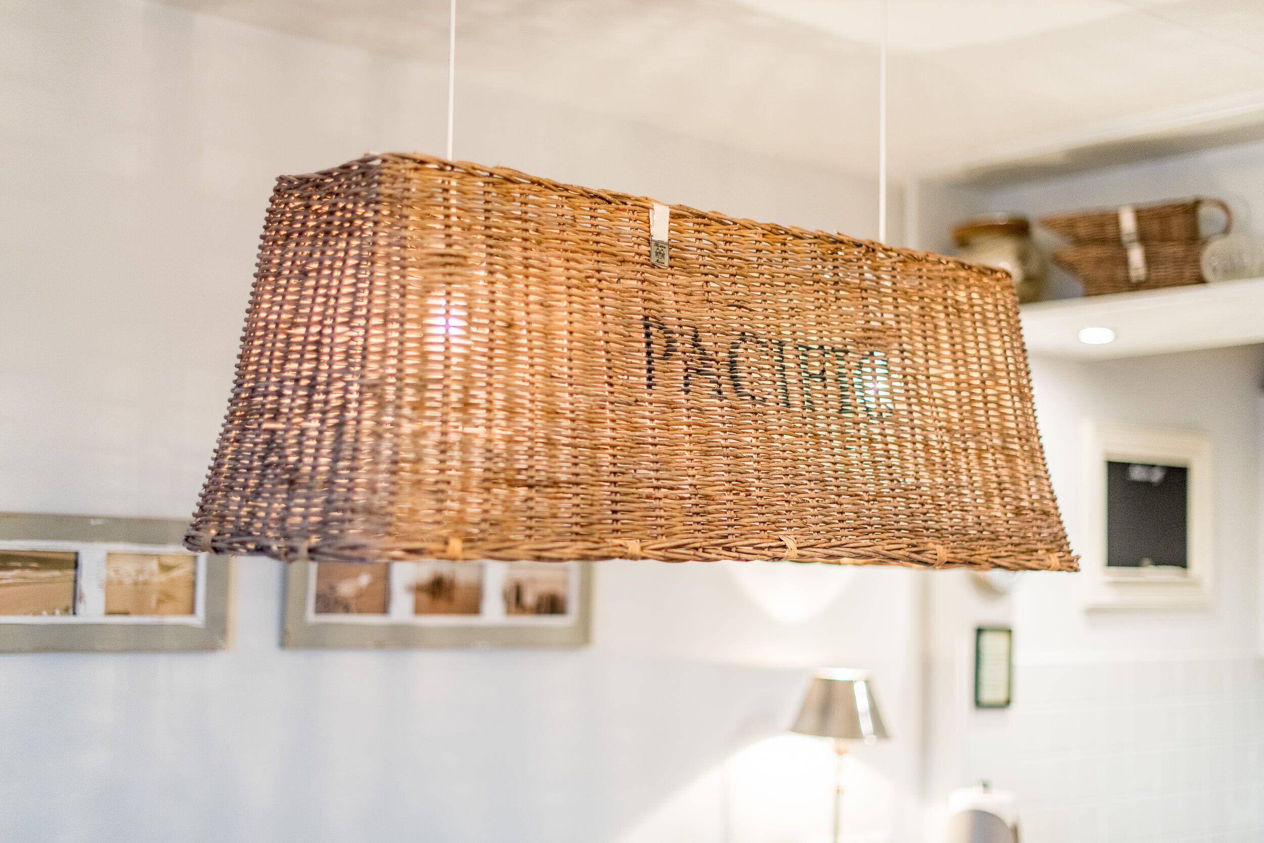Un panier tressé est suspendu au plafond dans une pièce dont les murs sont ornés de tableaux encadrés.