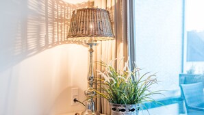 A lamp with a woven shade, a potted plant with white flowers, and a decorative item on a windowsill. - Exklusiv. Zentral. Strandnah (Westerland)