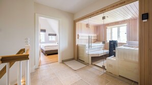 Habitación de hotel moderna con interior de madera, puerta de vidrio a un balcón y cama con vistas.
