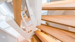 Una escalera con escalones de madera y barandillas blancas, que conduce a un piso superior.