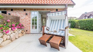 Una casa con fachada de ladrillo, techo de tejas y un porche con una silla a rayas y escalones de madera.