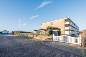 A modern multi-story building with a flat roof and a stone wall.