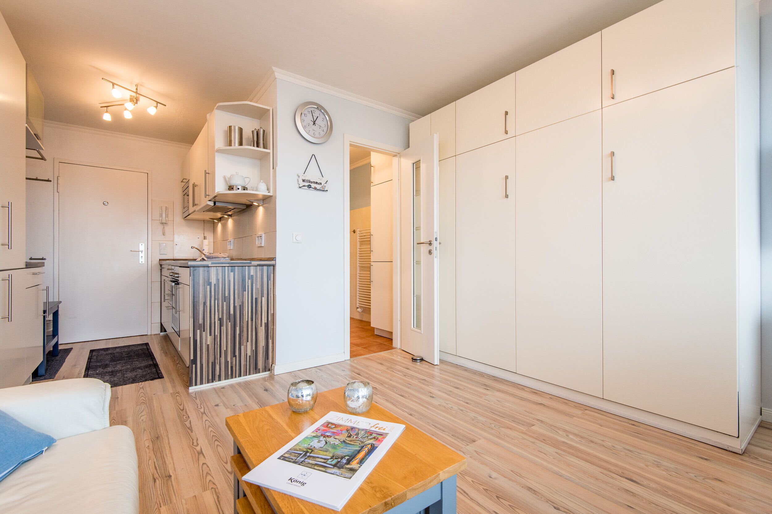 Eine kompakte Wohnung mit Küchenzeile, einem Essbereich mit Tisch und Stühlen sowie einem großen Kleiderschrank.
