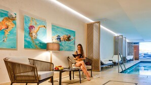 Un moderno vestíbulo de hotel con zona de piscina, destacando obras de arte, asientos y vistas a la piscina.